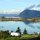 im Wasser spiegeln sich die Berge unter hellem Himmel