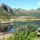 im Wasser spiegeln sich die Berge unter hellem Himmel