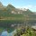 im Wasser spiegeln sich die Berge unter hellem Himmel